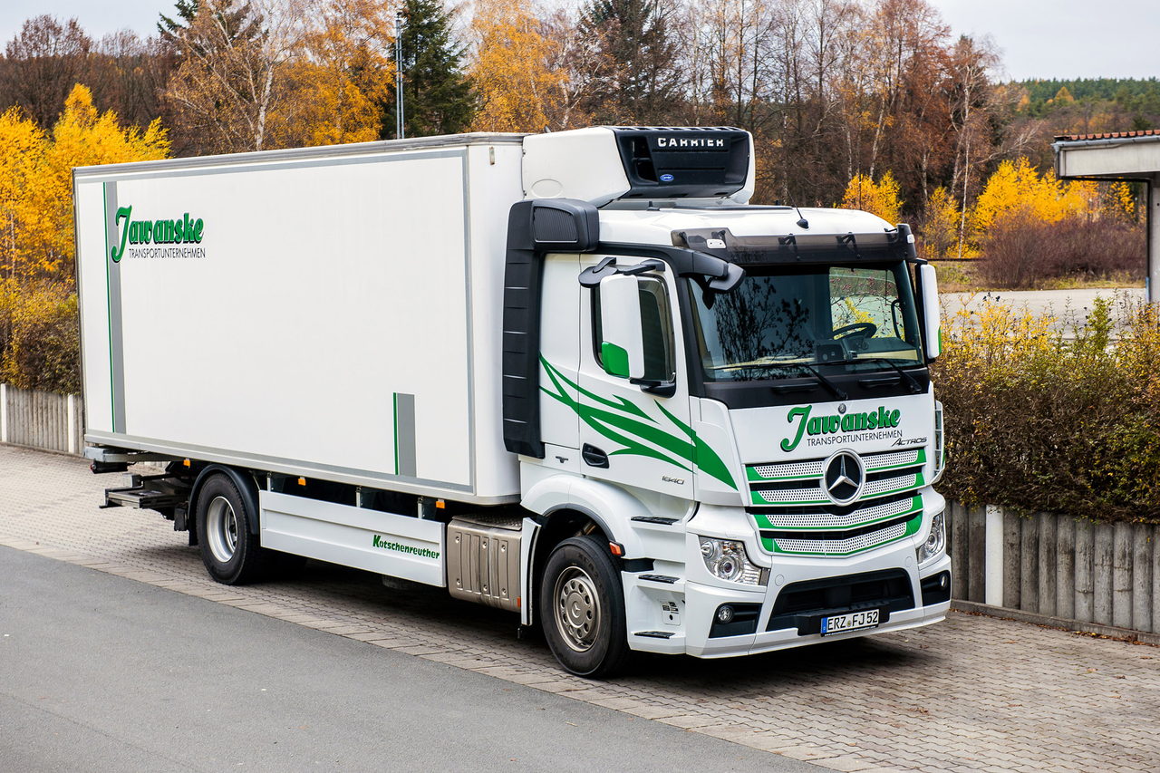 Weißer Mercedes-Benz LKW mit grüner "Juraschek" Beschriftung und Kühlaufbau parkt auf einer Straße.